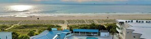 Resort com piscina, palmeiras e vista para a praia.
