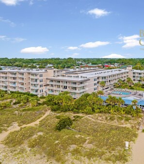 A beachfront hotel with multiple buildings, a pool area, and a beach access path.