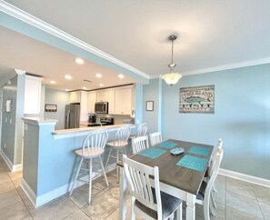 A modern kitchen with white cabinets, stainless steel appliances, and a bar area.