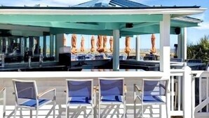 An outdoor seating area with umbrellas, chairs, and a covered patio. - Summer & July 4th Savings at Beachside Colony Tybee's ONLY Oceanfront Resort 3/2 (Tybee Island)