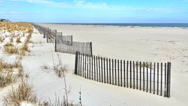 A sandy beach with a wooden fence running parallel to the shore. - Summer & July 4th Savings at Beachside Colony Tybee's ONLY Oceanfront Resort 3/2 (Tybee Island)
