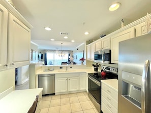 Una cocina moderna con armarios blancos, electrodomésticos de acero inoxidable y una isla grande con un lavamanos.