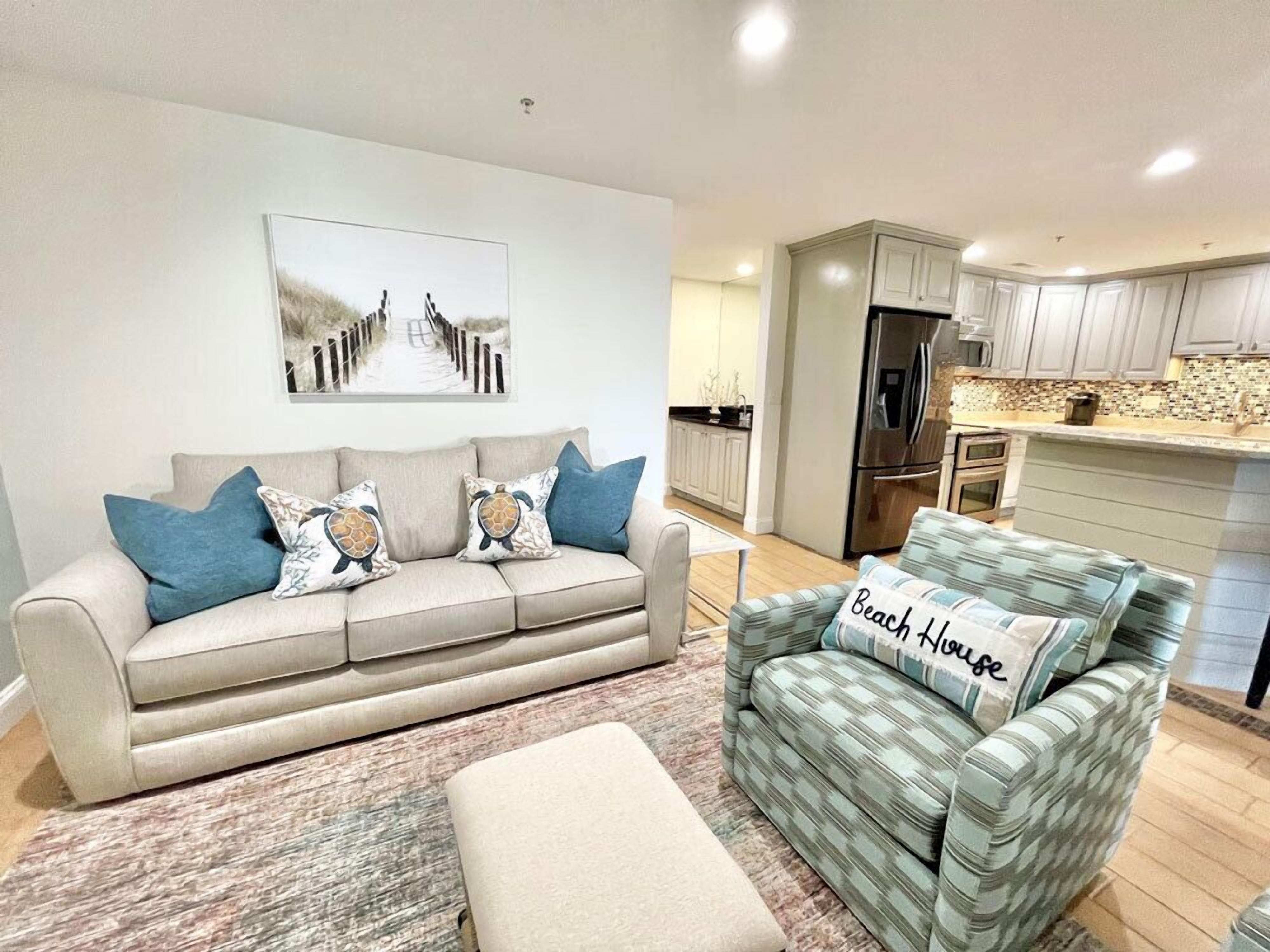 A living room with a beige sofa, a patterned armchair, and a rug.