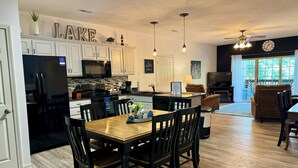 A modern kitchen with white cabinets, a black refrigerator, and a dining area with a wooden table and chairs. - Walk-in level Vickery Resort Lakefront Condo with Dock Access for your boat! (Hollister)