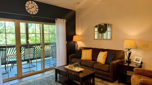 A living room with a dark brown sofa, two lamps, a clock, and a view of the outdoors through large sliding glass doors. - Walk-in level Vickery Resort Lakefront Condo with Dock Access for your boat! (Hollister)