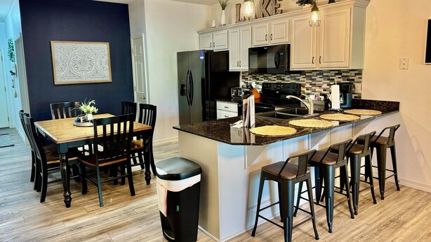 A modern kitchen with white cabinets, a black refrigerator, and a granite countertop. - Walk-in level Vickery Resort Lakefront Condo with Dock Access for your boat! (Hollister)