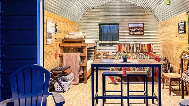 Un intérieur chaleureux avec une table en bois, des chaises, un canapé et une fenêtre agrémentée de rideaux.