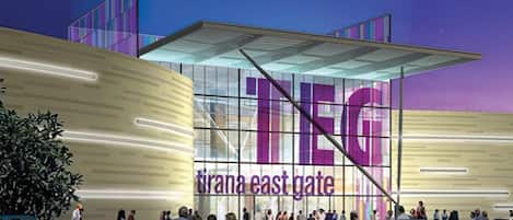 A modern building with a large glass facade and the text "TIRANA EAST GATE".