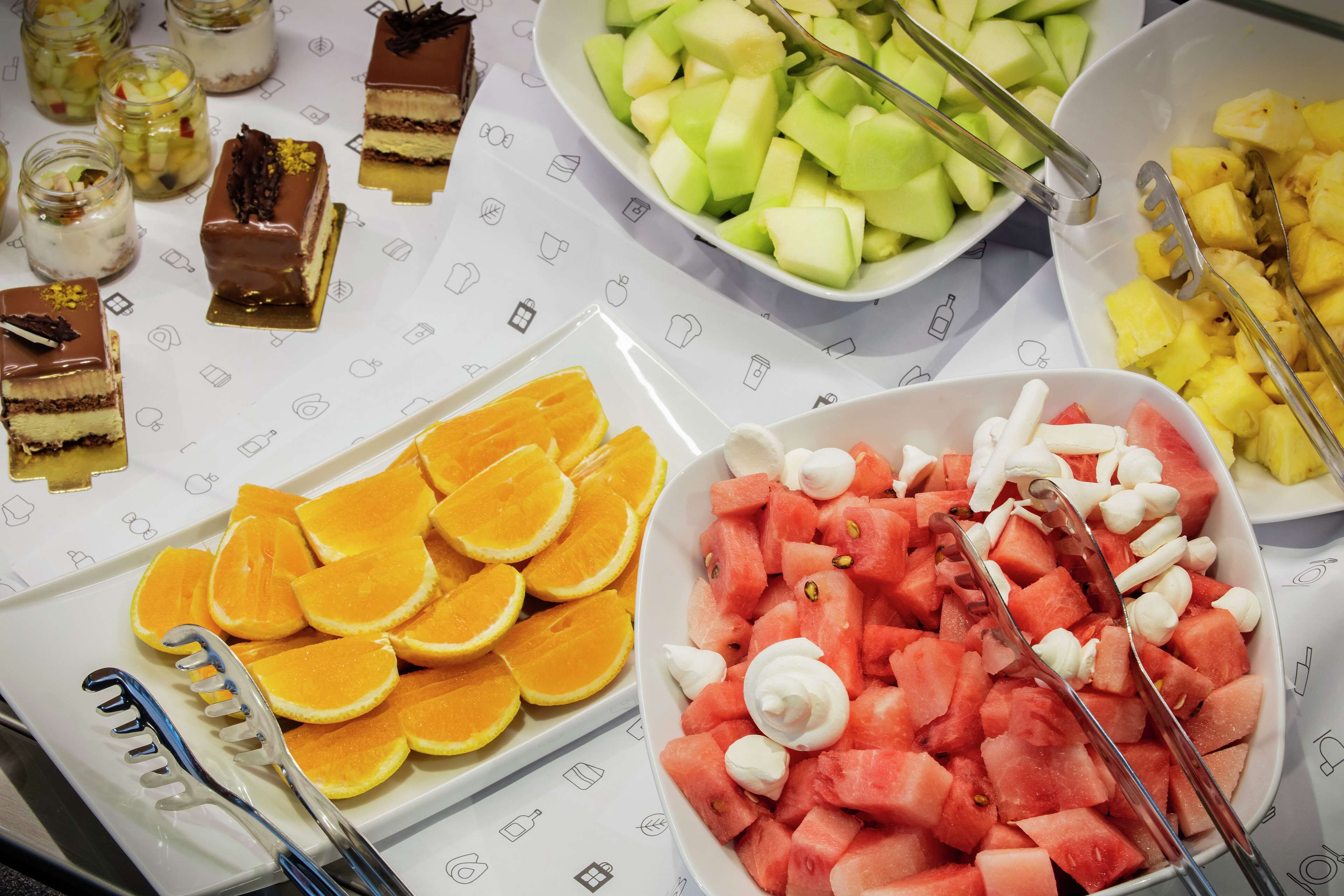 A buffet with various food items including watermelon, oranges, and desserts.