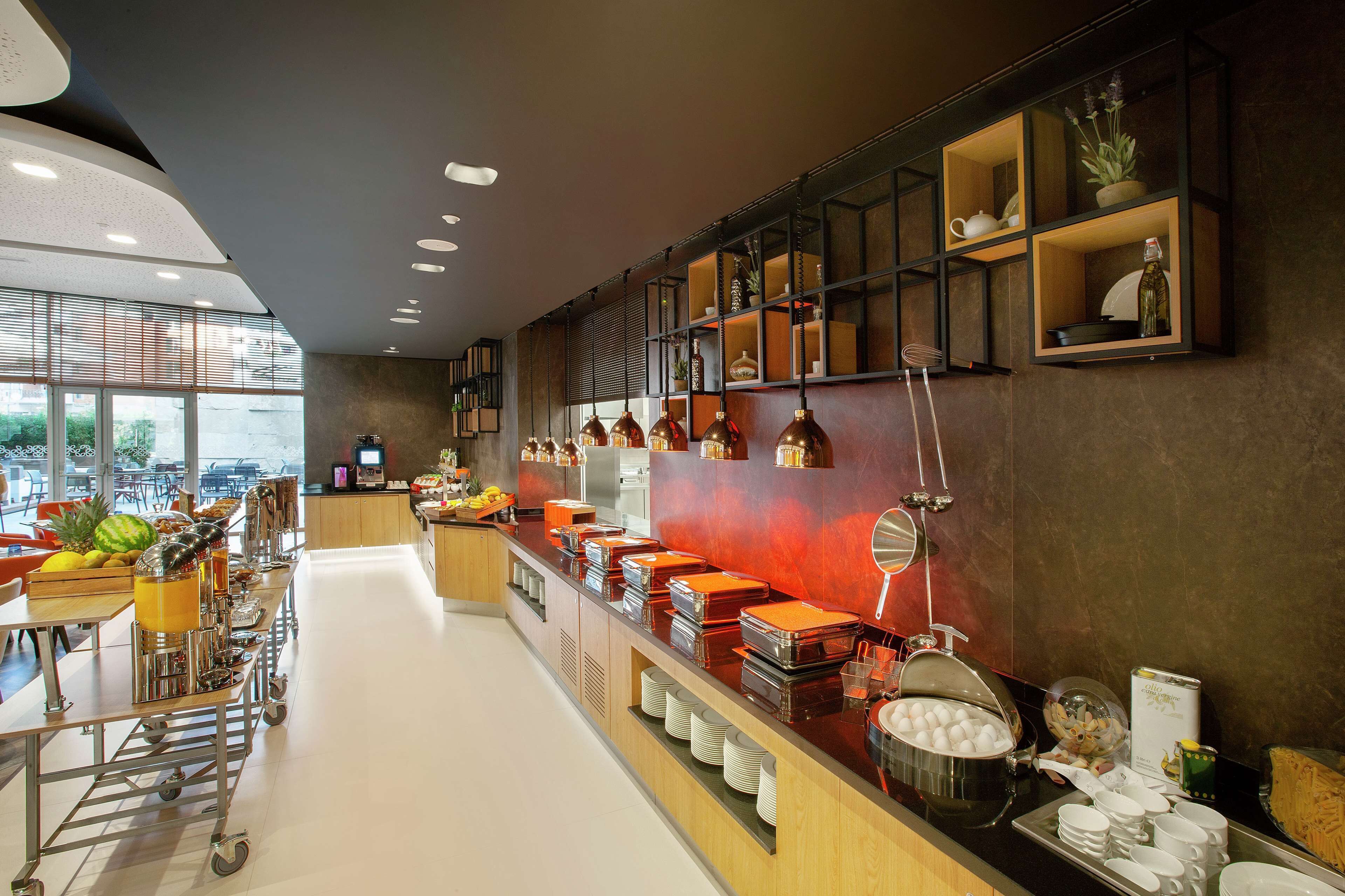 A modern breakfast buffet with a variety of food items and beverages, a coffee station, and a seating area with tables and chairs.