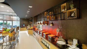 A modern breakfast buffet with a variety of food items and beverages, a coffee station, and a seating area with tables and chairs.