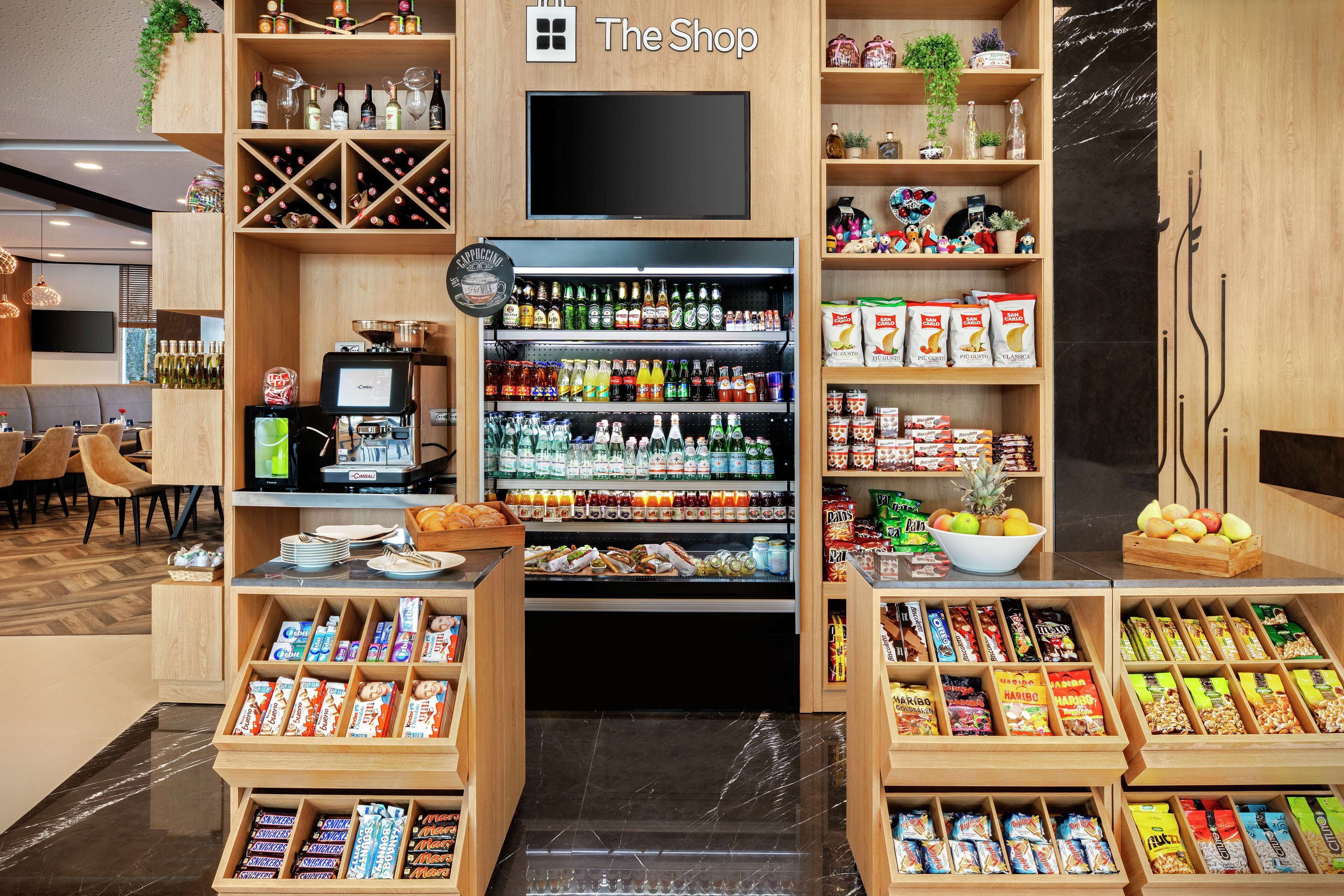 A shop with shelves stocked with snacks, beverages, and a TV screen.