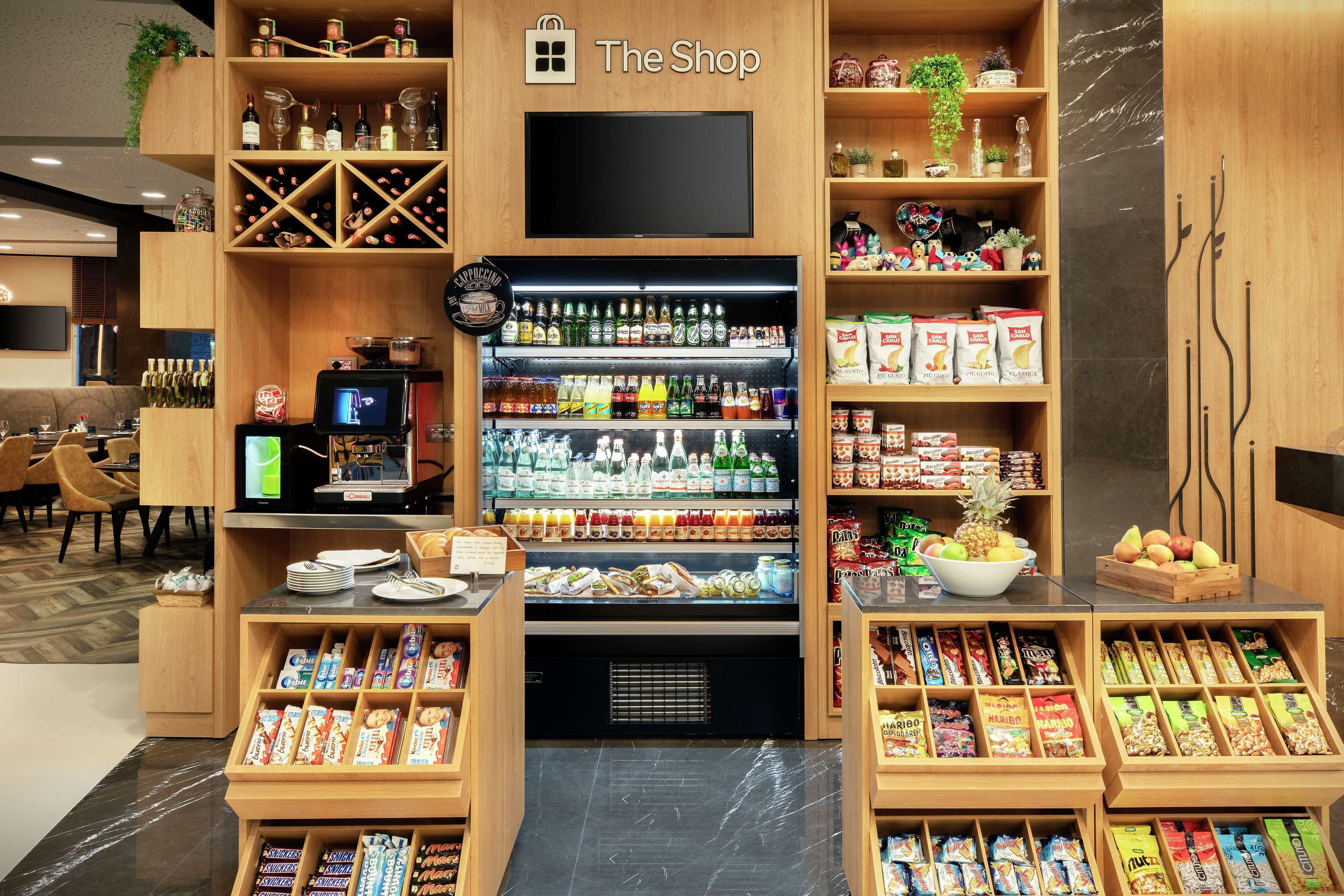 A shop with shelves stocked with snacks, beverages, and a television.