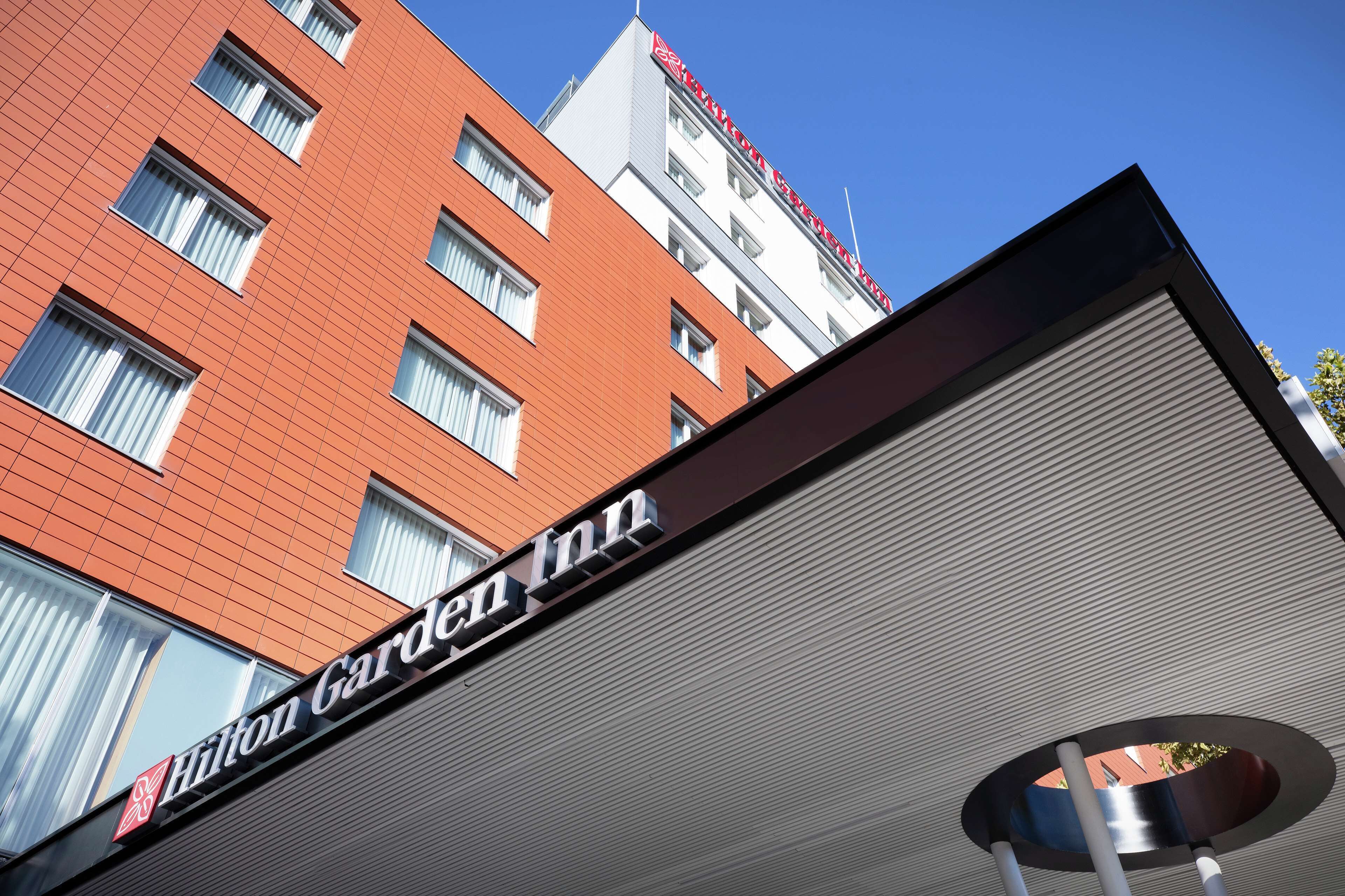 A Hilton Garden Inn building with a red facade and multiple windows.