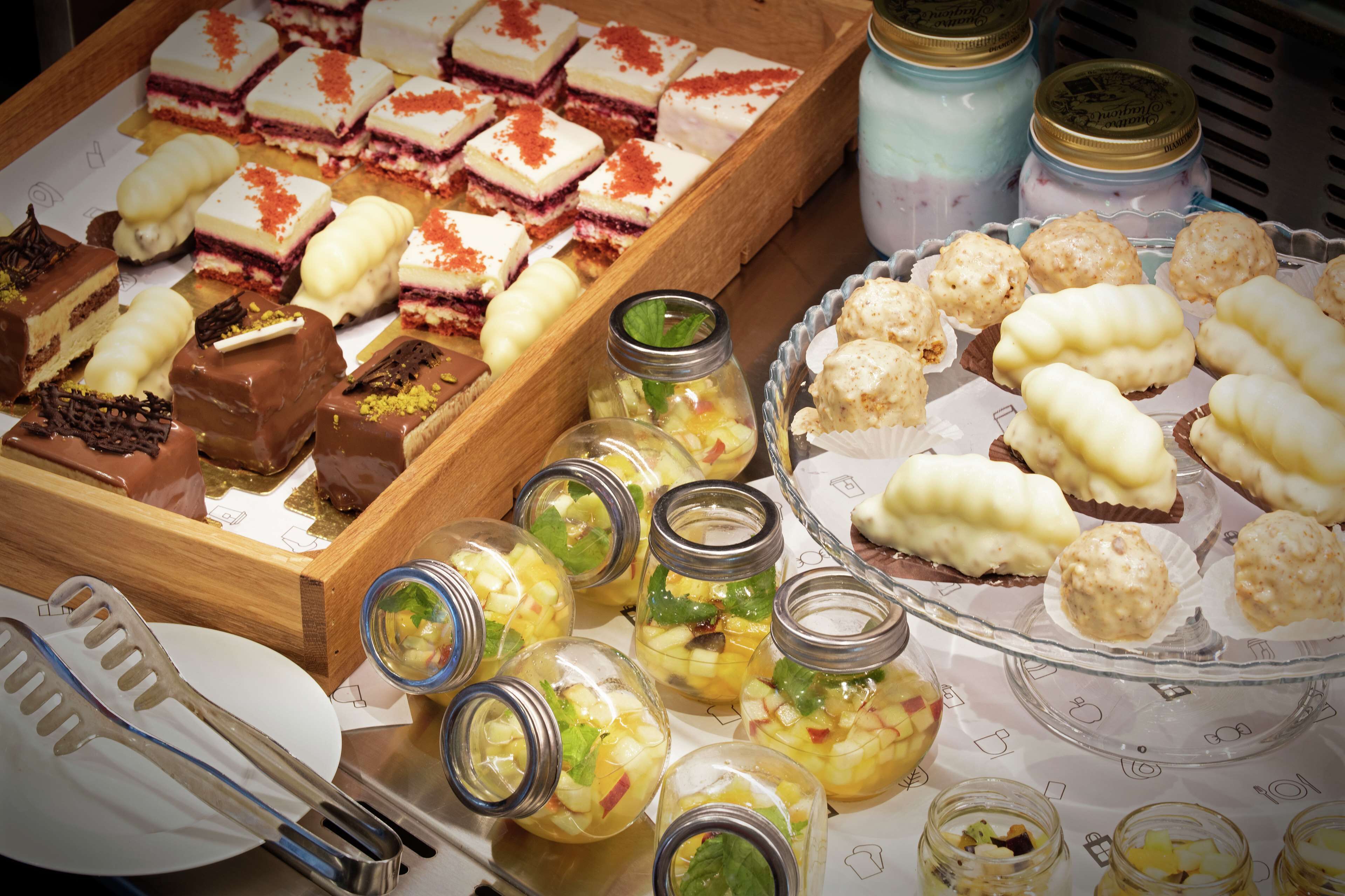 Eine Auswahl an Desserts und Snacks auf einem Tisch, darunter Gläser mit eingelegten Früchten und Gebäck.