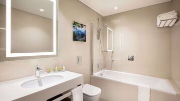 Un baño moderno con un espejo grande, un lavabo, un inodoro y una bañera.