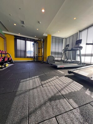 A gym with exercise equipment, a treadmill, and a weight rack. - Hilton Garden Inn Tirana (Tirana)