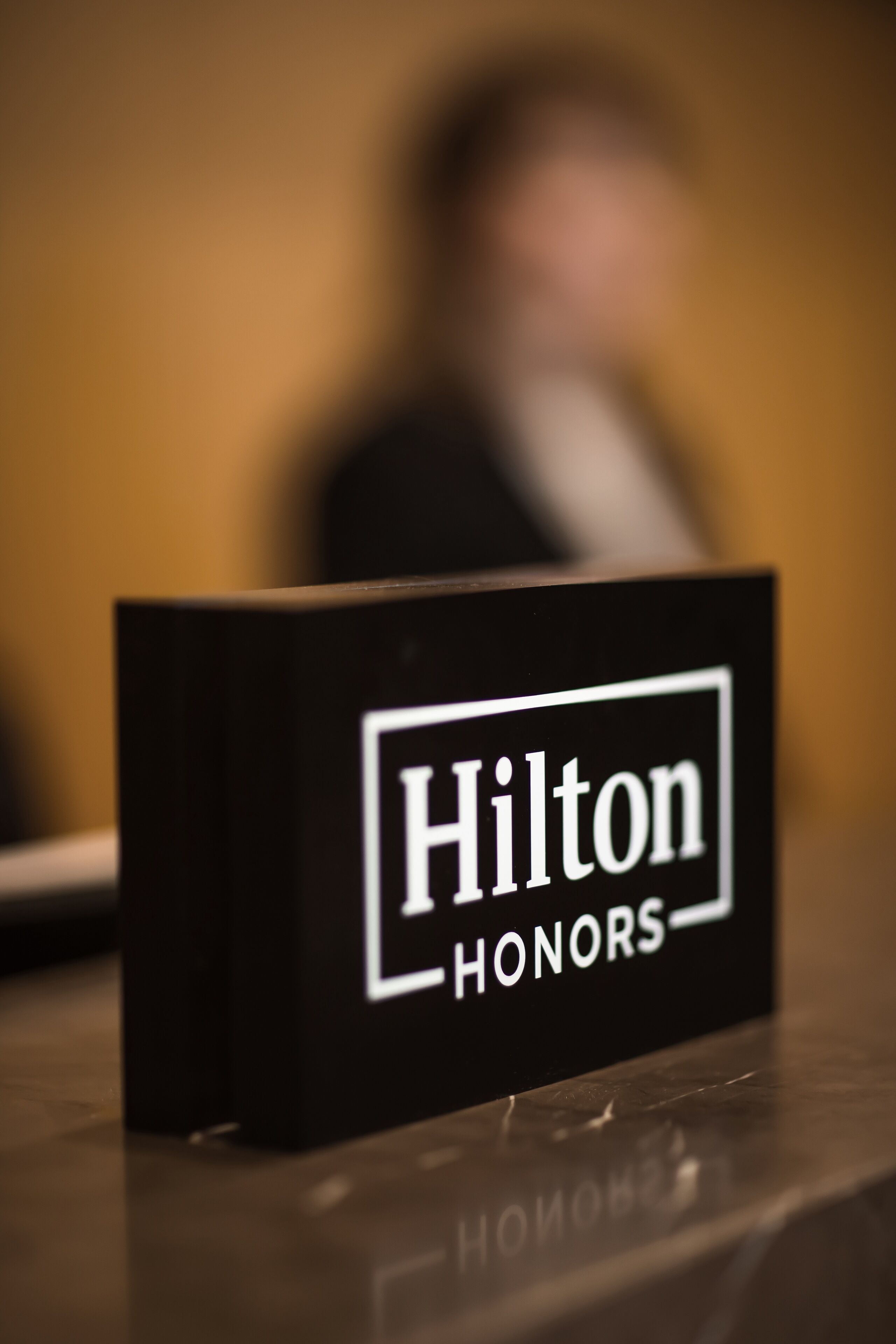Un panneau noir portant l’inscription « Hilton HONORS » sur une surface réfléchissante.