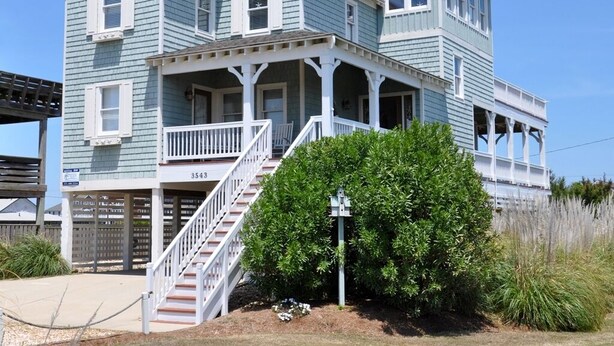 Ein zweistöckiges Haus mit Veranda, Treppe und Briefkasten.
