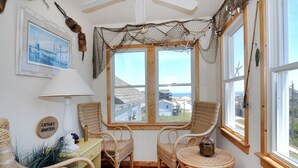 Ein gemütlicher Winkel mit Korbstühlen, einem kleinen Tisch und Blick aufs Meer durch ein mit Netz versehenes Fenster.