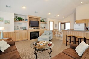 Relax in a spacious living area with a central seating area, entertainment unit, and fireplace.