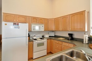 Kitchen equipped with a refrigerator, microwave, stove, toaster, and coffee maker.