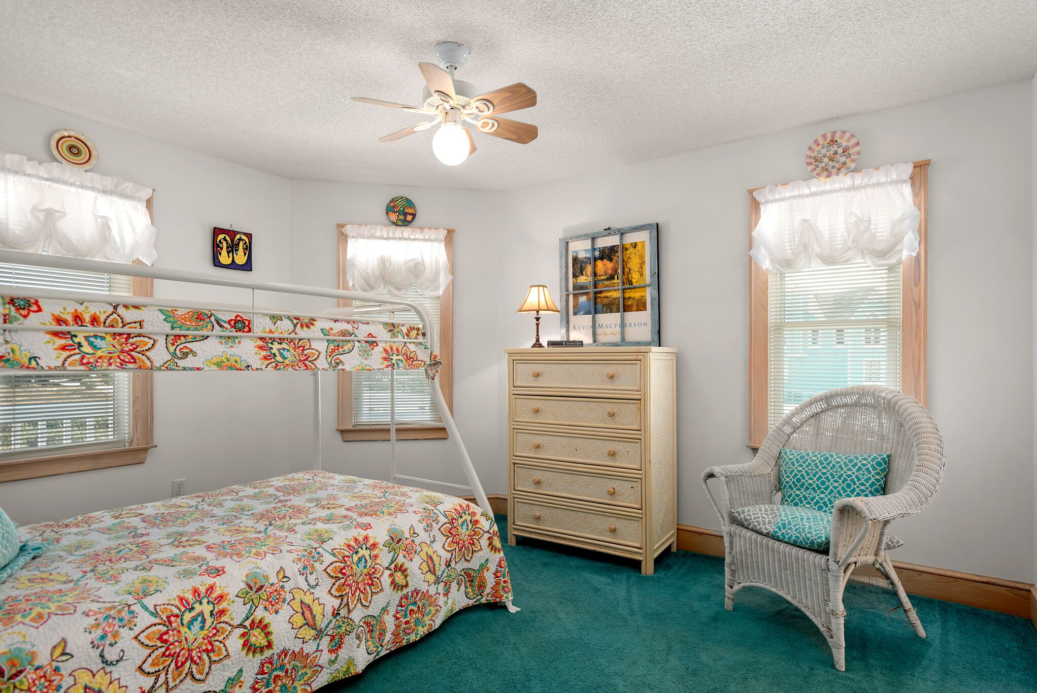 A bedroom with a bunk bed, a dresser, a chair, and a ceiling fan.