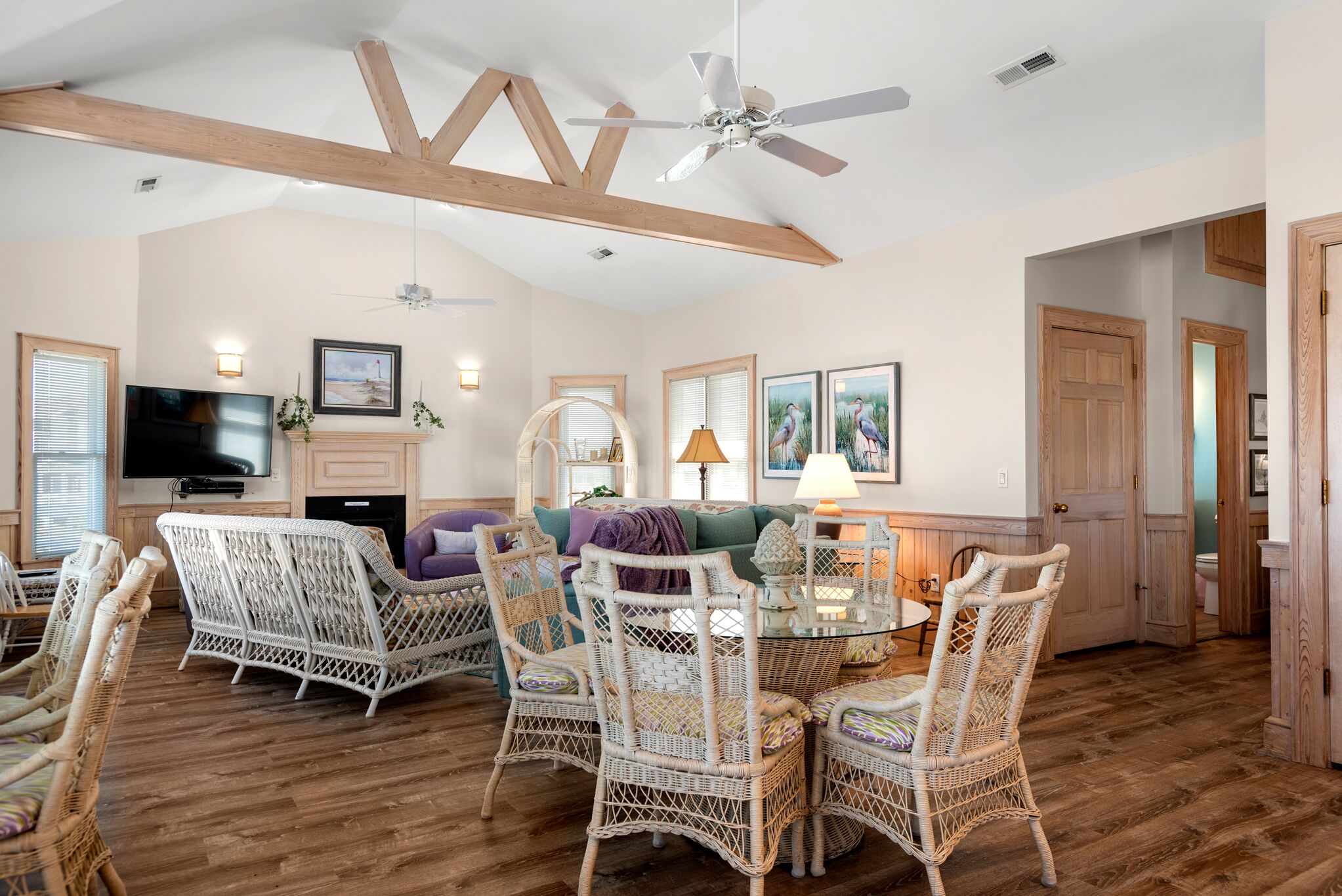 A spacious living room with wicker furniture, a fireplace, and a ceiling fan.