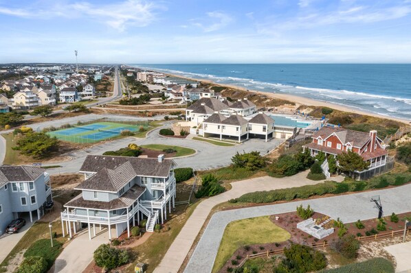 A coastal residential area with houses, a tennis court, and a beach view.