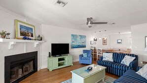 Ein Wohnzimmer mit Kamin, Fernseher, Sofa und Deckenventilator.