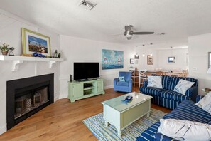 A living room with a fireplace, television, sofa, and a ceiling fan.