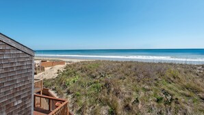 Blick auf einen Strand mit einer Holzterrasse und einem Gebäude.