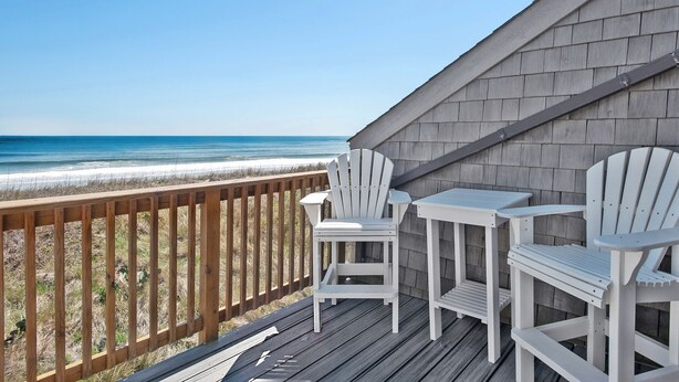 Eine Holzterrasse mit Blick auf Strand und Meer.