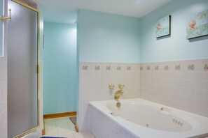 Une salle de bain avec une baignoire blanche, des murs bleu clair et des carreaux décoratifs.