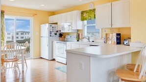 Une cuisine moderne avec des meubles blancs, un îlot central et un coin repas doté de chaises en bois.