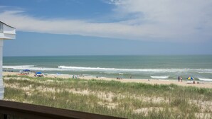 A beach view from a balcony with a clear sky, sandy beach, and ocean waves. - Daniel's Diamond: Oceanfront, Great Views, Pool (Nags Head)