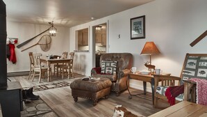 Ein gemütliches Wohnzimmer mit Ledersessel, Couchtisch aus Holz und einem Essbereich mit Holztisch und Stühlen.