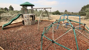 Une aire de jeux avec un toboggan, une structure d’escalade et des balançoires.