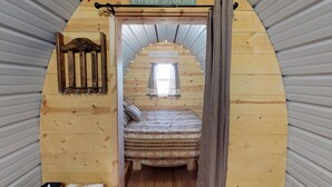 Un intérieur chaleureux, avec des murs en bois, un lit, une petite table et une pancarte sur laquelle on peut lire : « Faites de beaux rêves ».