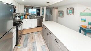 Cozinha moderna com armários brancos, eletrodomésticos de aço inoxidável e piso com padrão herringbone.
