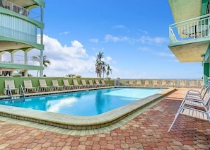 A swimming pool with lounge chairs, a brick patio, and a clear sky. - Chateaux Condominium 204- Beach front w/ spectacular views! (Indian Shores)