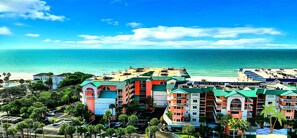 Un hotel frente a la playa con edificios coloridos, un estacionamiento y vista al océano.