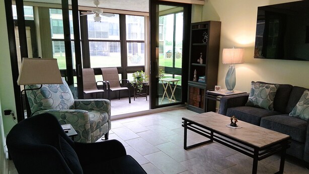 A living room with a sofa, armchair, coffee table, and a bookshelf.