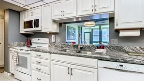 A modern kitchen with white cabinetry, a built-in microwave, a stove, and a dishwasher.