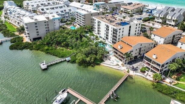 Una zona alberghiera sulla costa, con diversi edifici, un molo e una piccola isola ricoperta di vegetazione.
