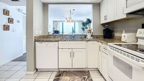 Una cucina moderna con mobili bianchi, un piano di lavoro in granito e un forno integrato.
