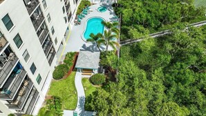 Un hotel moderno con piscina, immerso nel verde e dotato di un pontile che si protende sull'acqua.