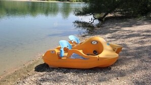 Ein kleines Schlauchboot liegt am Kiesufer eines Sees.