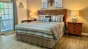 Ein Schlafzimmer mit einem großen Bett, zwei Nachttischen mit Lampen, einem Deckenventilator und Kunstwerken an den Wänden.