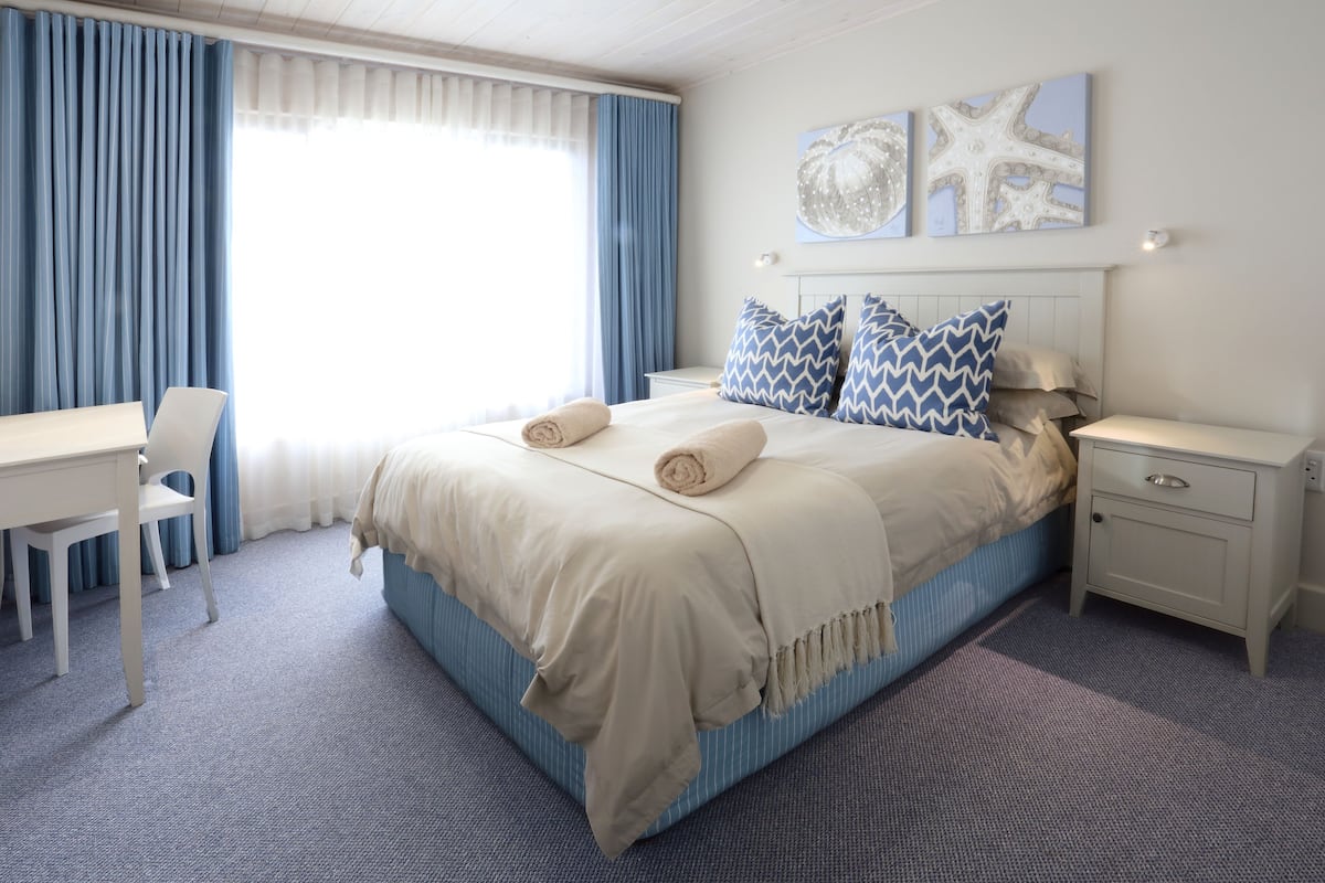 Ein Schlafzimmer mit Bett, Nachttischen, Schreibtisch und Stuhl.